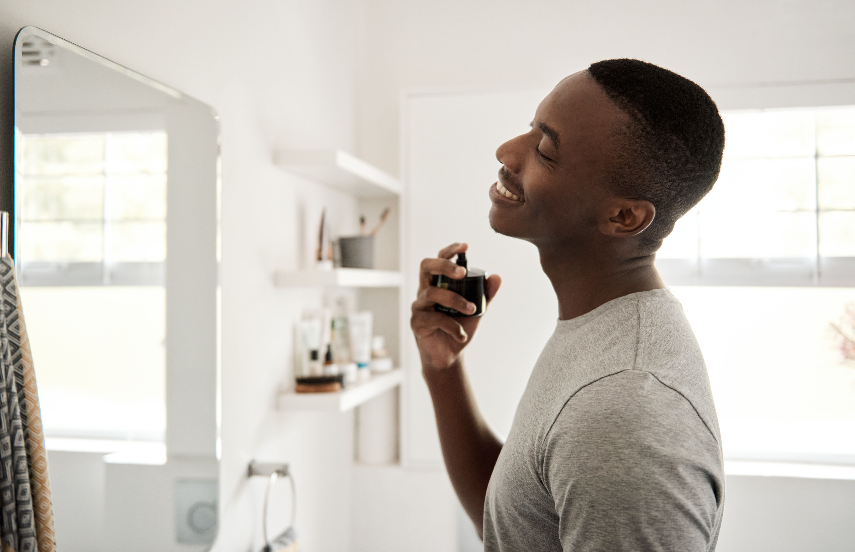 Person spraying cologne on their neck.