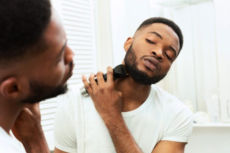 A man trimming his beard in the mirror