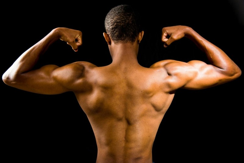 topless man back muscles flexing muscles with black background